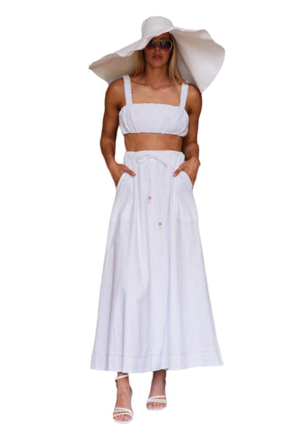 White crop top with matching full skirt and styled with large straw hat, sunnies and white heels.