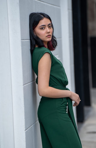 Side view of green jumpsuit with pockets and tie waist.