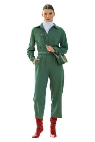 Green jumpsuit layered for winter with white skivvy and red boots.