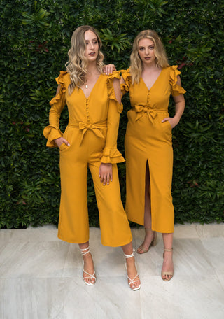 Two models one wearing the mustard jumpsuit with long sleeves and the other wearing the dress with short sleeves.