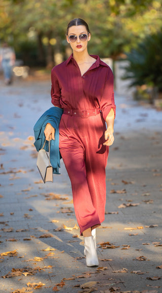 Jumpsuit street styled with white boots and white bag.