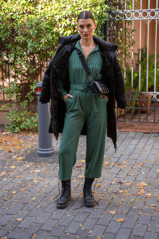 Forest green jumpsuit styled with black accessories and black puffer coat.