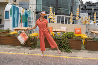 Beach style jumpsuit styled with sandal, viser and beach bag.