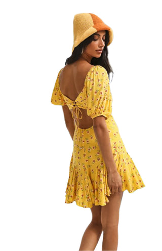 Side view of yellow floral print mini dress with cut out back.