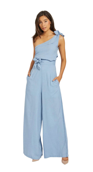 One shoulder jumpsuit in light blue linen fabric with tie shoulder and tie waist.