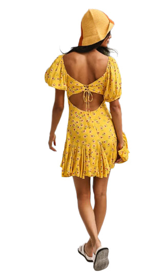 Yellow printed dress street styled with sandals and cap.