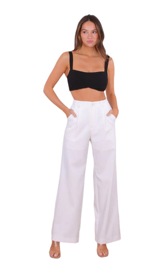 Model wearing high waisted white pants with pockets styled with black crop top.