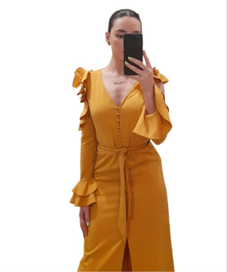 Close up of mustard maxi dress with button detail, ruffle arm and wrist detail and tie waist.