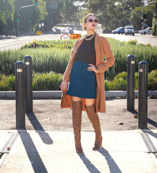 Brown long line jacket with blue high waisted a-line mini skirt and thigh high brown boots.