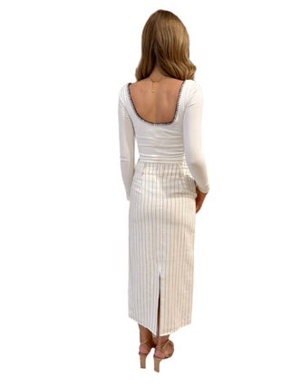 Back view of long sleeve white fitted top with low rounded back and contrast black stitching.