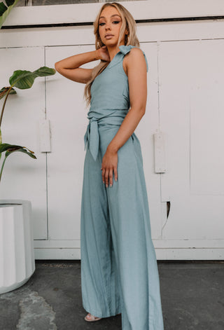 Side view of jumpsuit with pockets, wide leg and fitted one shoulder top.