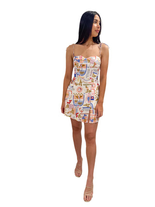 Beautiful model wearing postcard print mini dress with tie straps and nude heel
