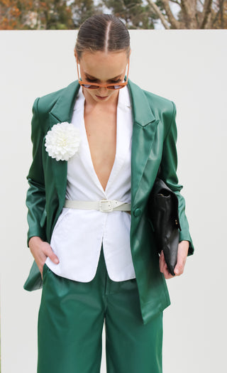 Model wearing the vegan leather blazer styled with a white vest and white accessories.