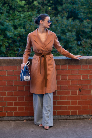Brown long line jacket done up with jeans and contrasting belt.