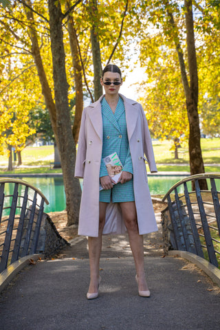 Model wearing matching blazer and short suit with wool blend cream coat over shoulders and points.