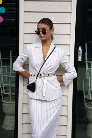 Street style white linen pinstripe blazer and matching skirt belted with a cross body bag.