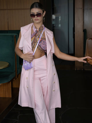 Woman in a stylish outfit with a pink vest and pants in an indoor setting.