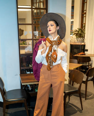 Chic style brown high waisted, wide leg pant styled with crisp white shirt, hat and neck scarf.