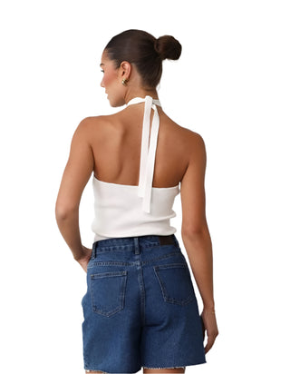 Back view ofwhite halter top styled with denim shorts.